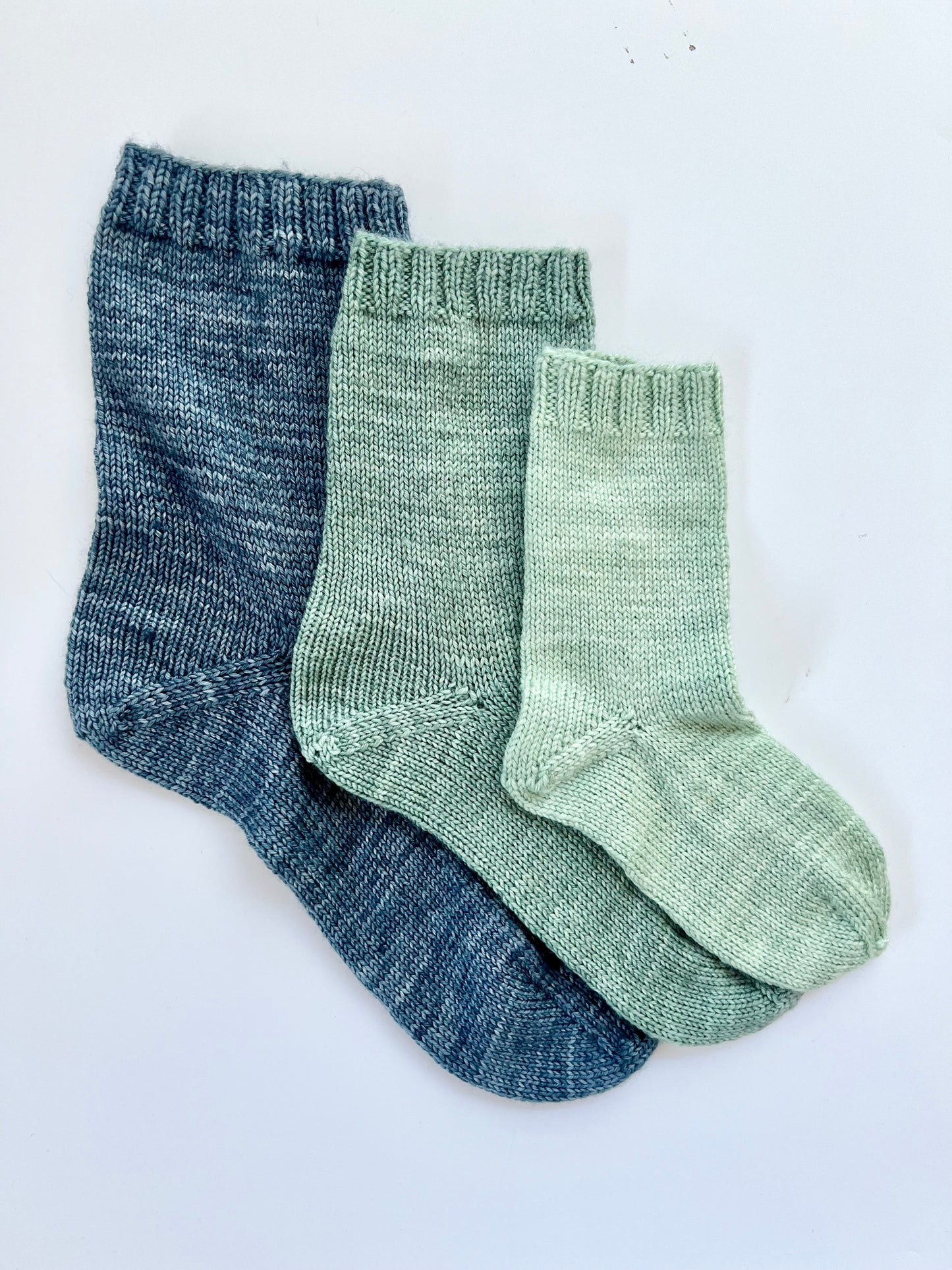 Three pairs of socks, one blue and two green, on a white background.