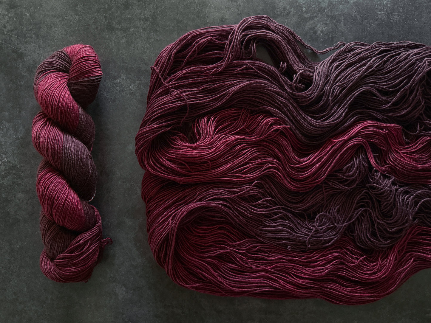 Skeins of dark red yarn on a textured gray background