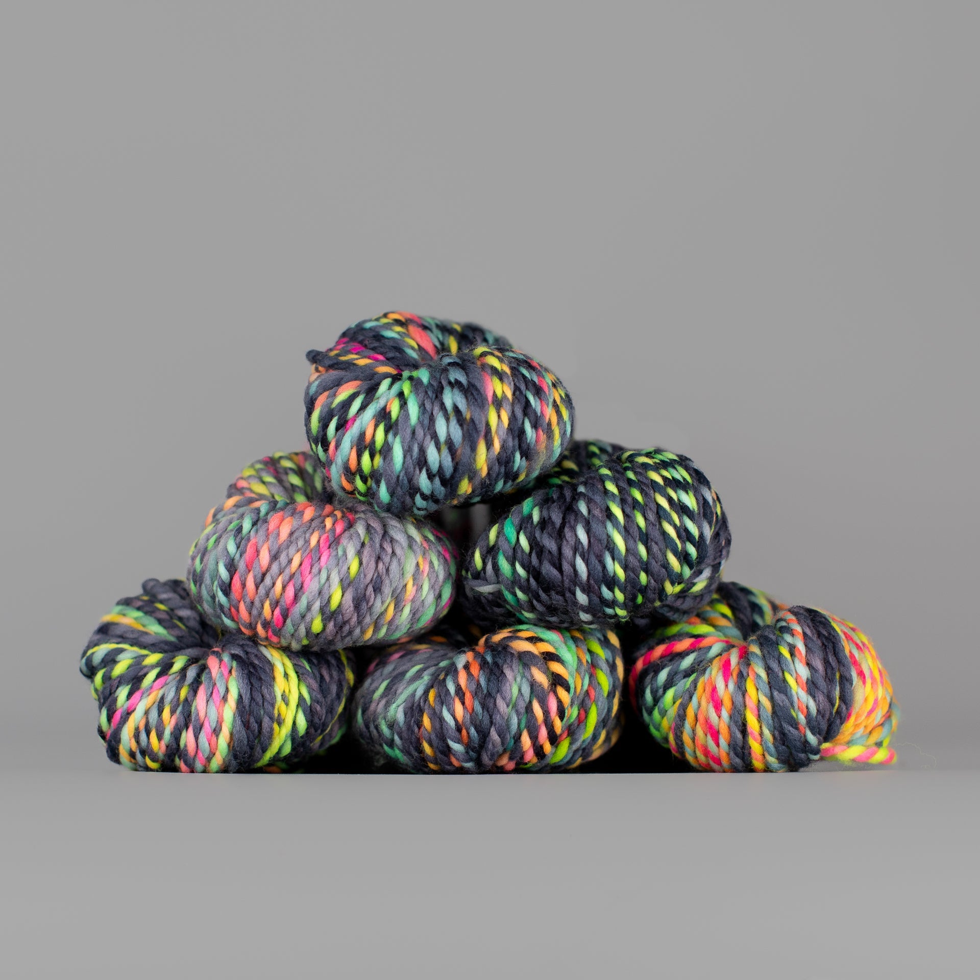Skeins of Spincycle Plump Bulky weight yarn in black, blue, yellow, pink, and orange color gradient