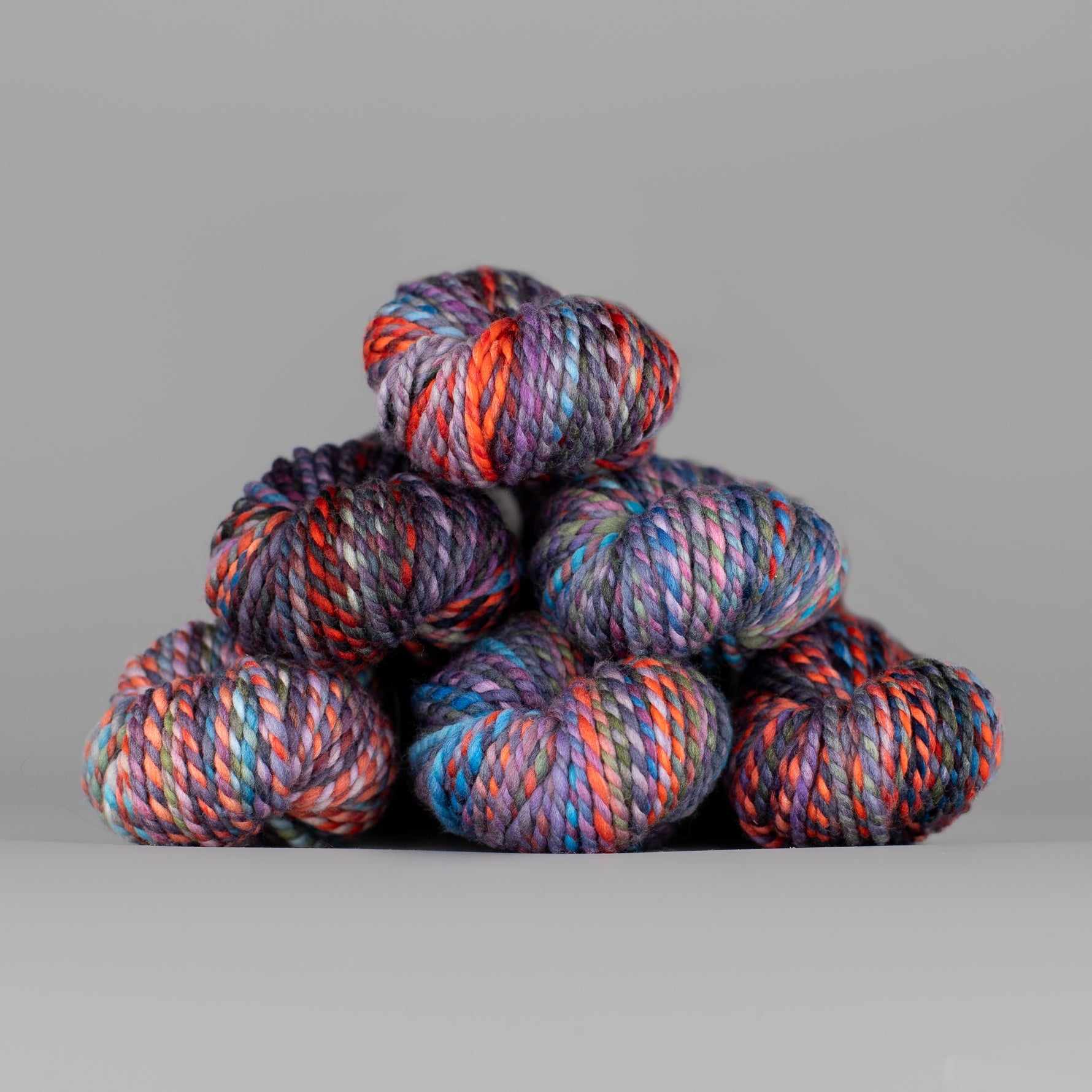 Skeins of Spincycle Plump Bulky weight yarn in pink, blue, purple, and red color gradient