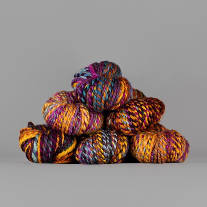 Skeins of Spincycle Plump Bulky weight yarn in yellow, purple, brown, and blue color gradient