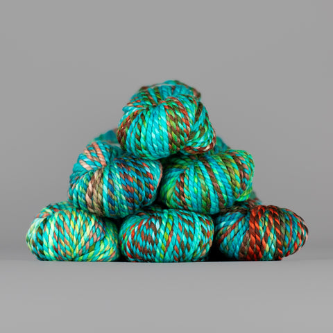Skeins of Spincycle Plump Bulky weight yarn in aqua blue, teal green, and red color gradient