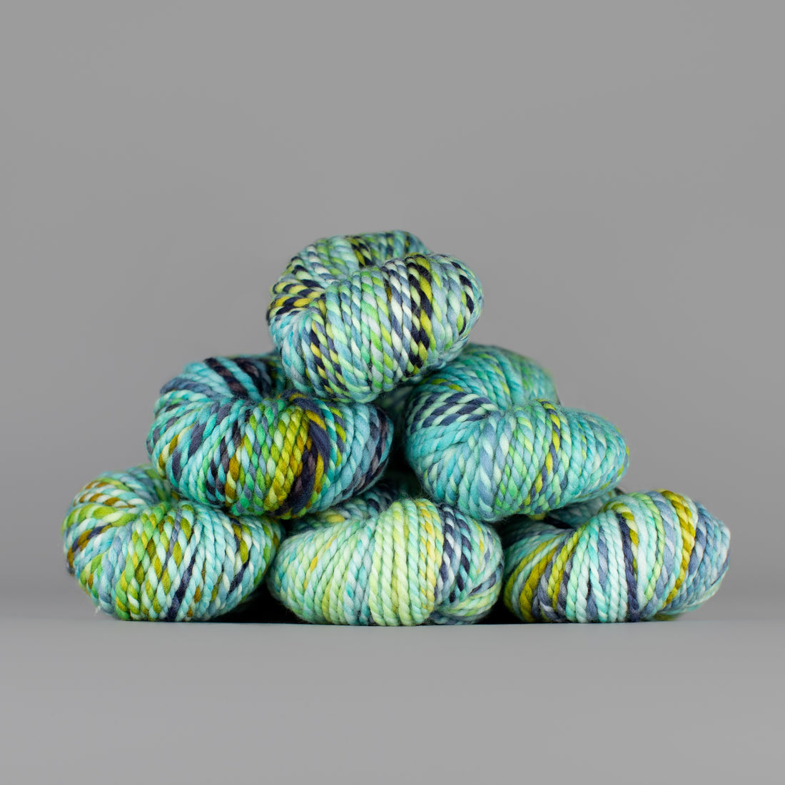 Skeins of Spincycle Plump Bulky weight yarn in blue, grey, and yellow color gradient