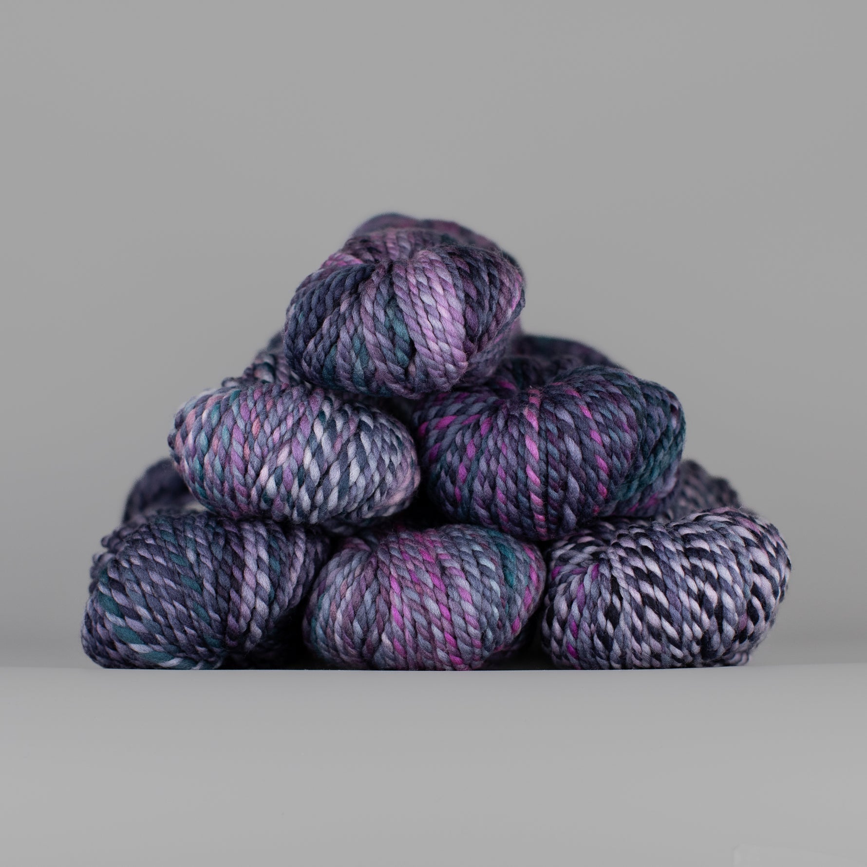 Skeins of Spincycle Plump Bulky weight yarn in purple, mauve, blue, black, and white color gradient