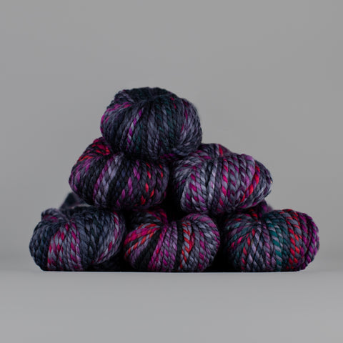 Skeins of Spincycle Plump Bulky weight yarn in purple, dark blue, pink, and grey color gradient