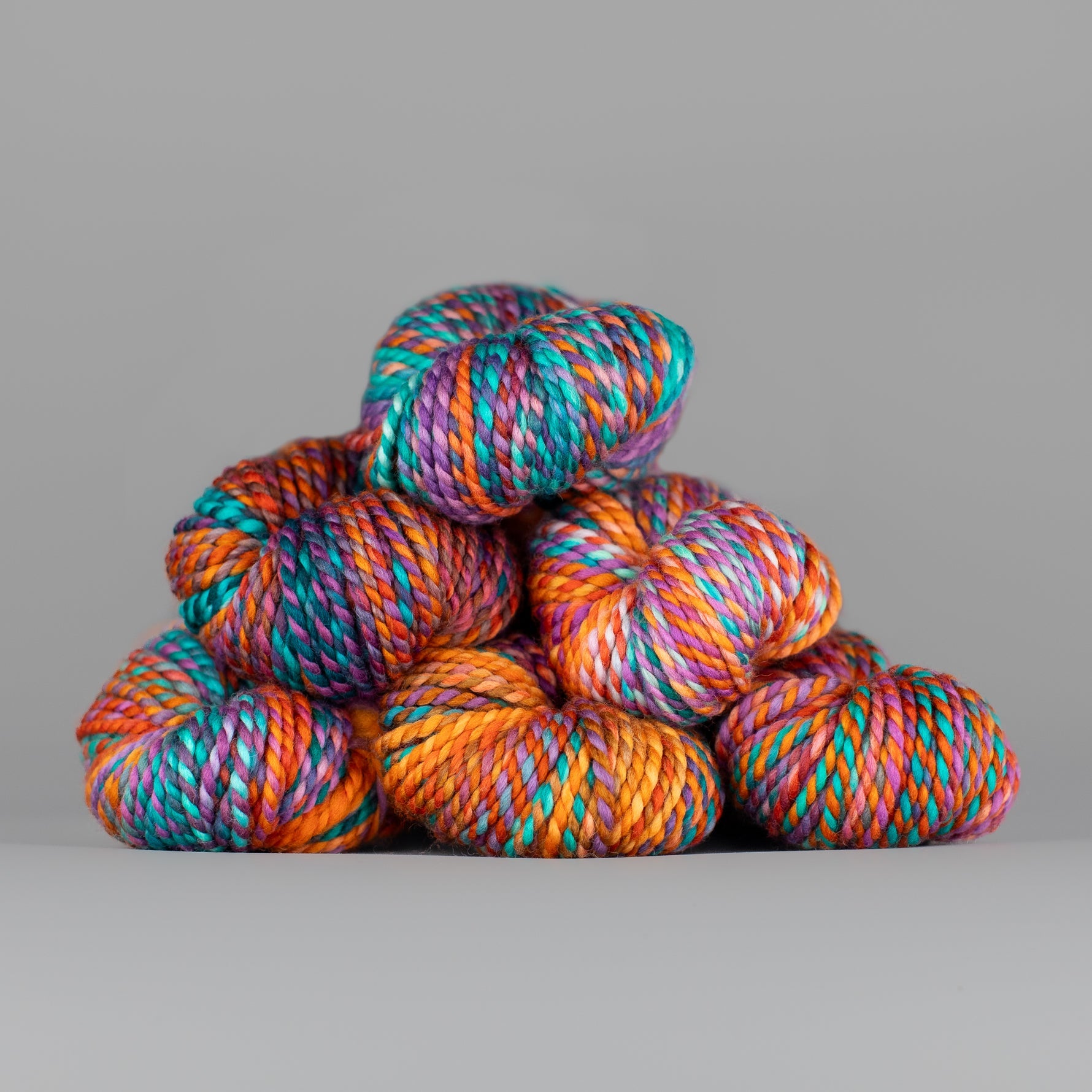 Skeins of Spincycle Plump Bulky weight yarn in orange, pink, aqua blue, and purple color gradient