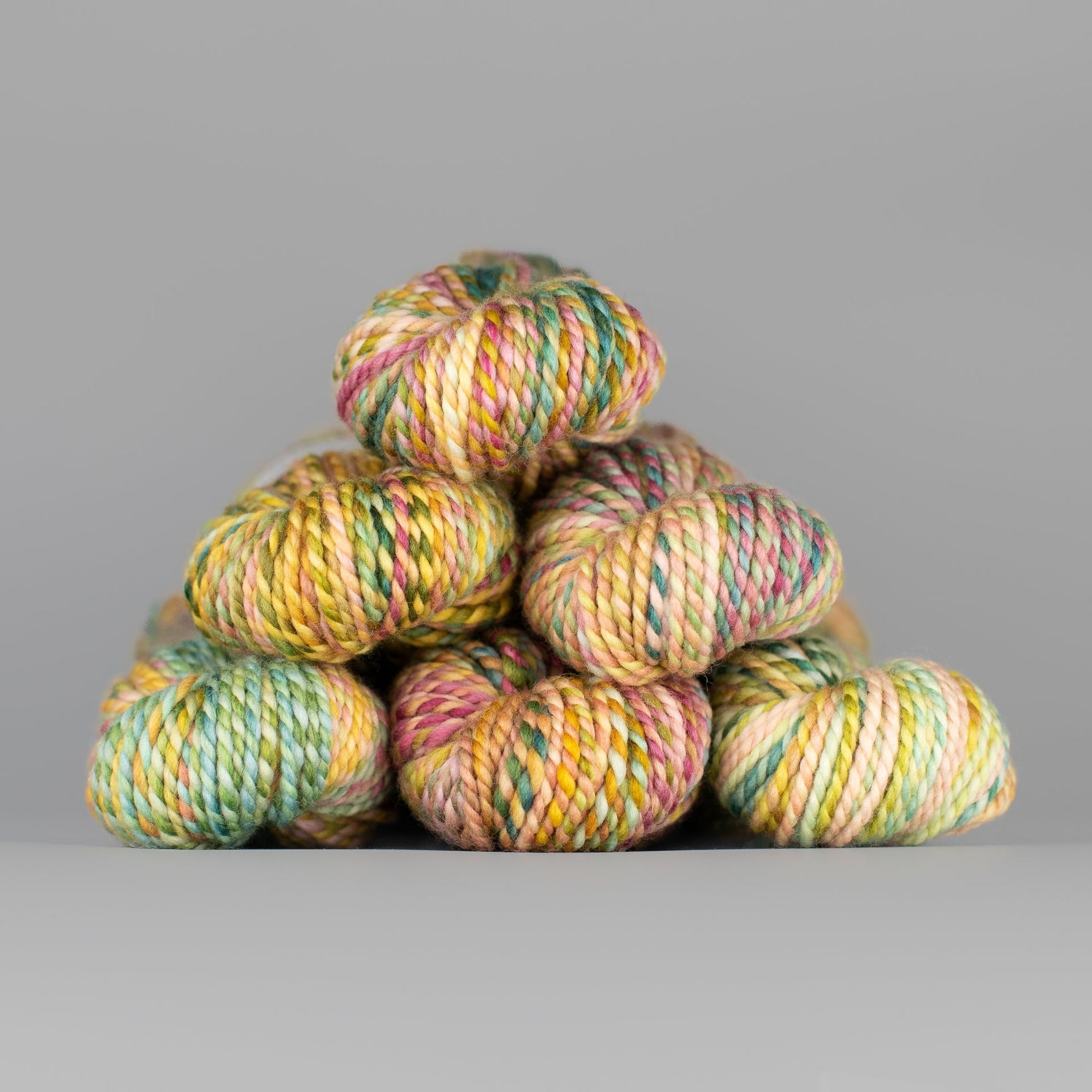 Skeins of Spincycle Plump Bulky weight yarn in yellow, green, and pink color gradient