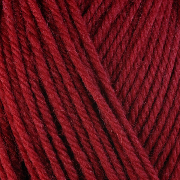 A close-up image of a skein of Berroco Ultra Wool bulky weight yarn in a deep red color.