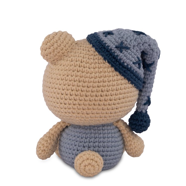Crocheted teddy bear wearing blue pajamas on a white background