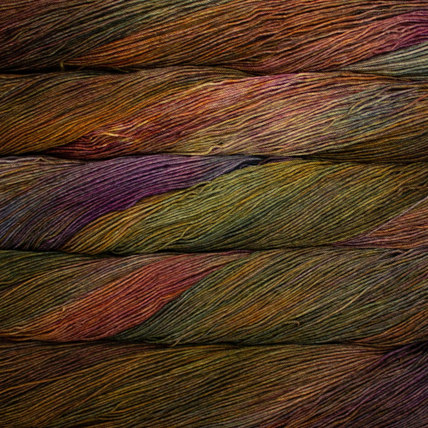 Close-up of multicolored yarn strands in purple, rust, green, and yellow