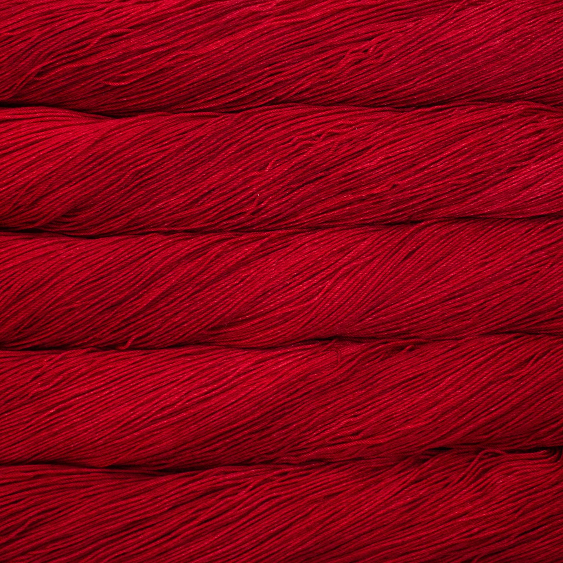 A close up of a skein of Malabrigo Ultimate Sock fingering weight yarn in vibrant red color