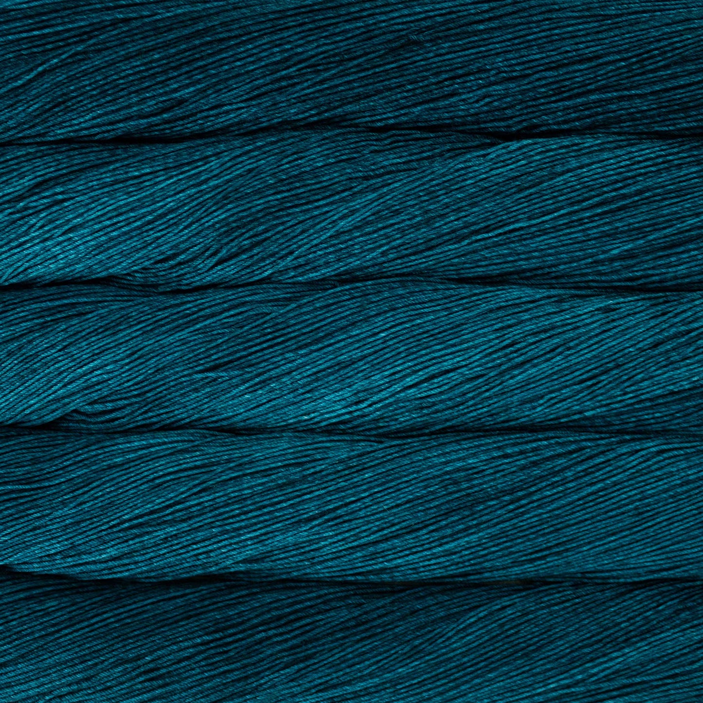 A close up of a skein of Malabrigo Ultimate Sock fingering weight yarn in dark teal blue color