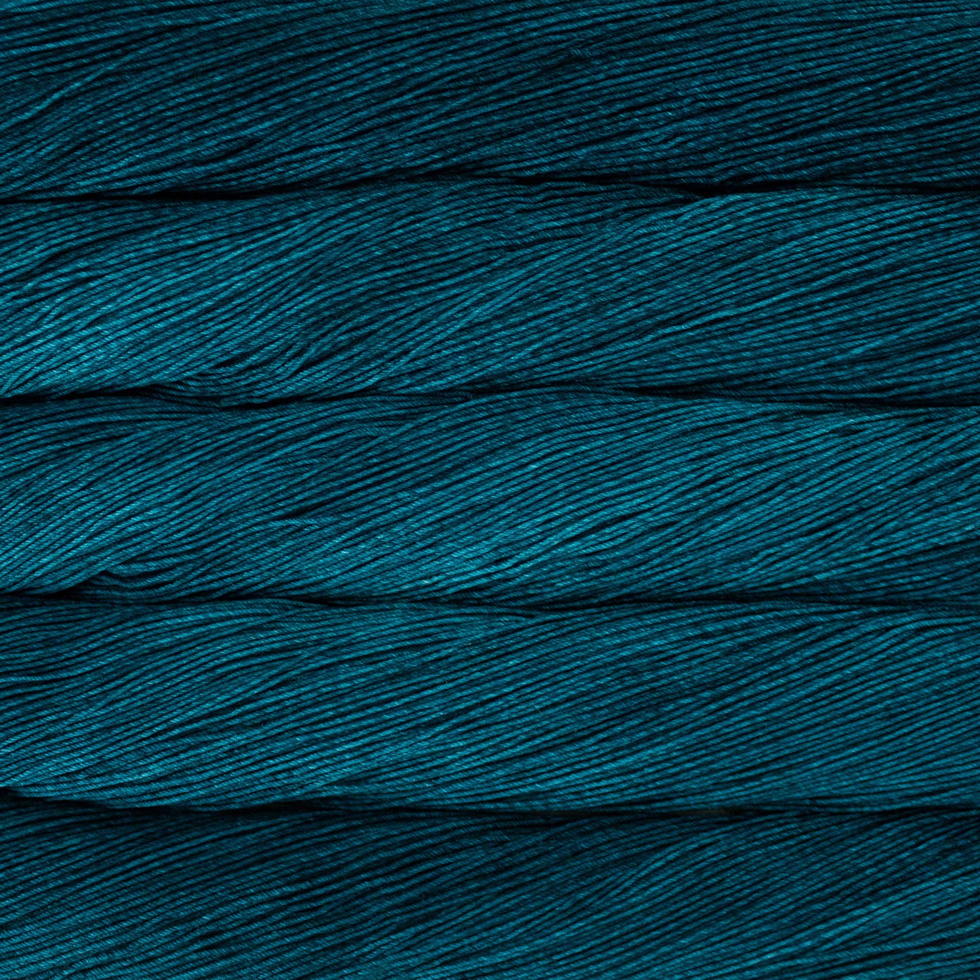 A close up of a skein of Malabrigo Ultimate Sock fingering weight yarn in dark teal blue color