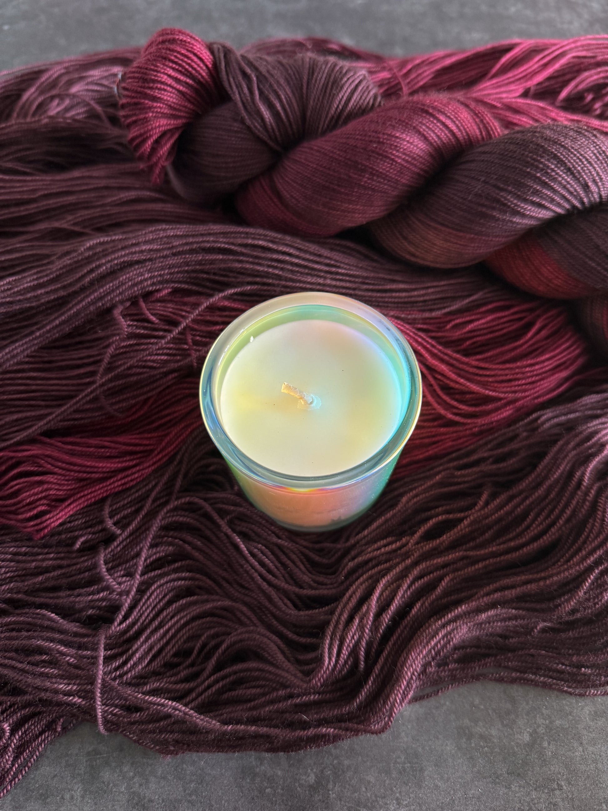 Candle in a glass holder on a skein of red yarn