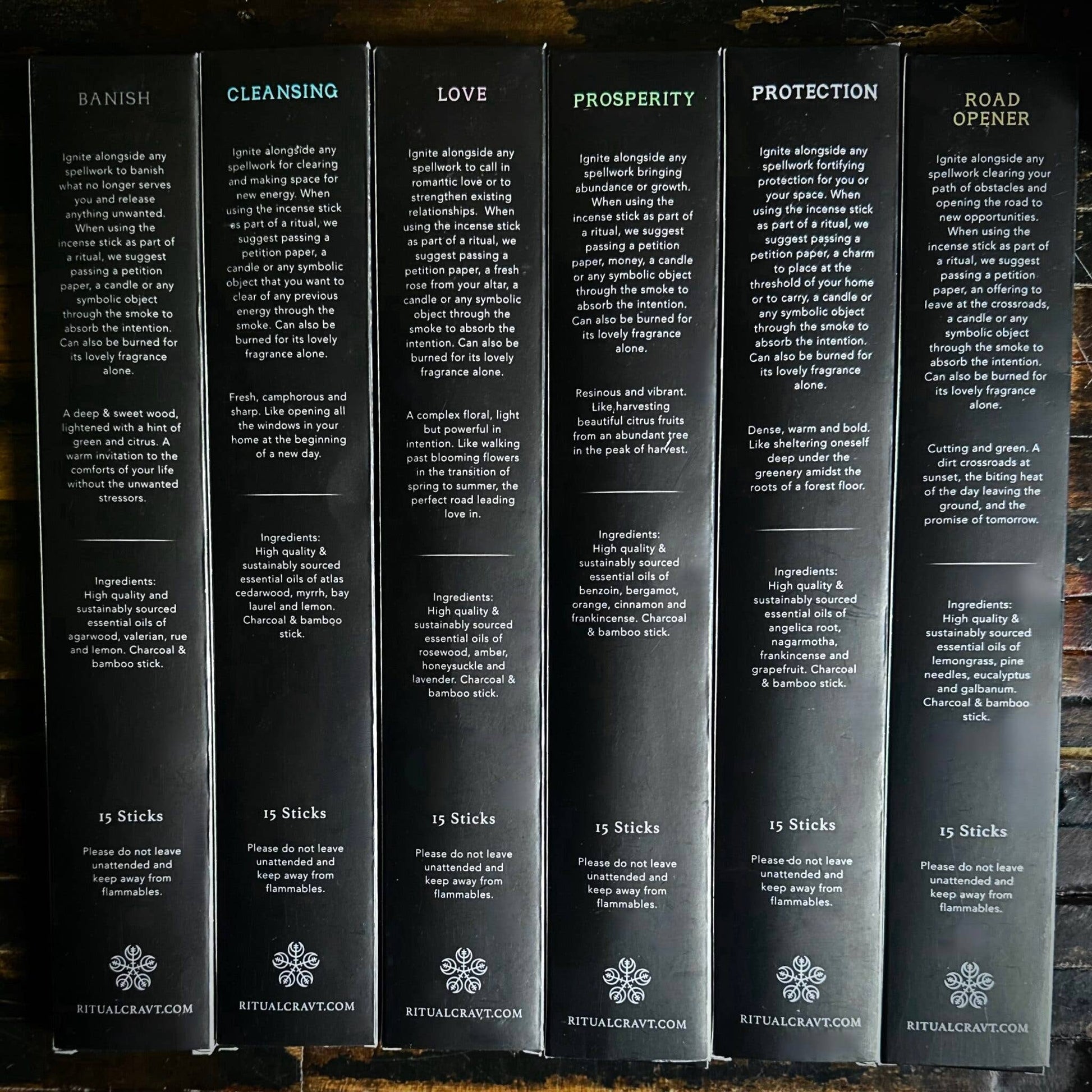 Set of six black boxes of incense labeled with different categories on a wooden surface.
