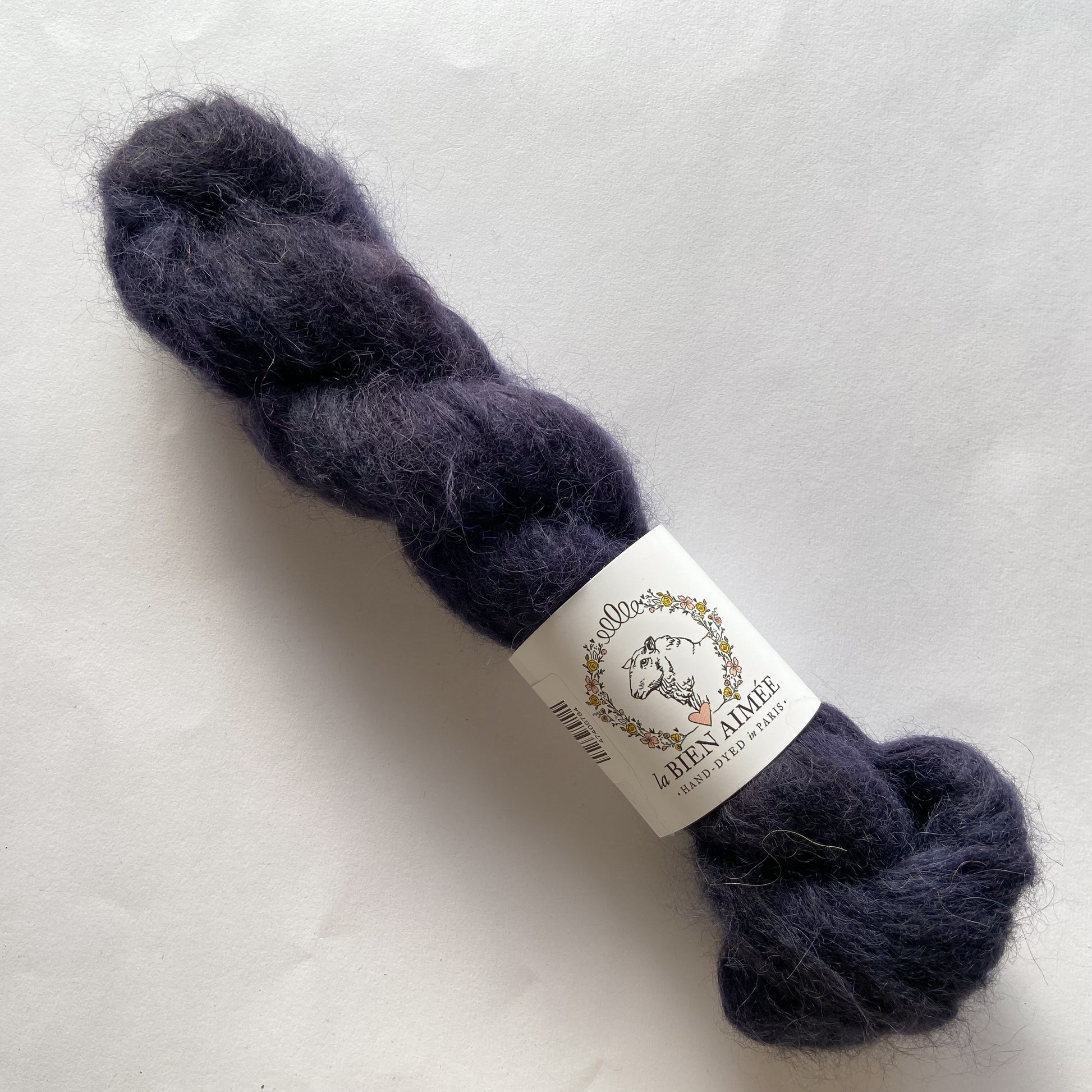 An image of a skein of La Bien Aimee lace weight yarn in the color black with a white ‘La Bien Aimee’ label against a white background.