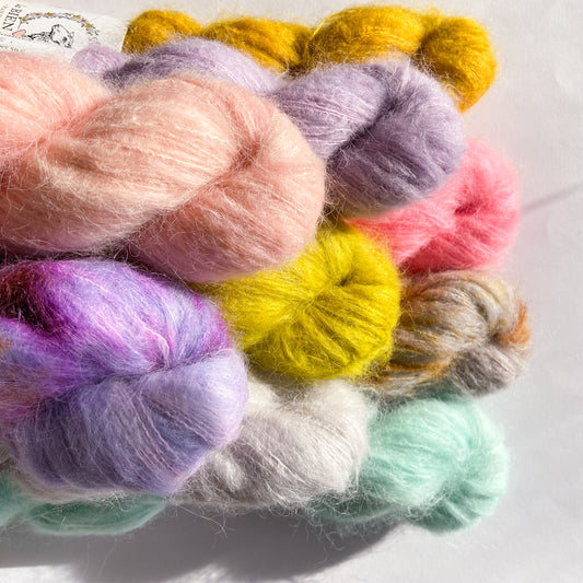 An image of multiple skeins of La Bien Aimee lace weight yarn in a variety of colors against a white background.
