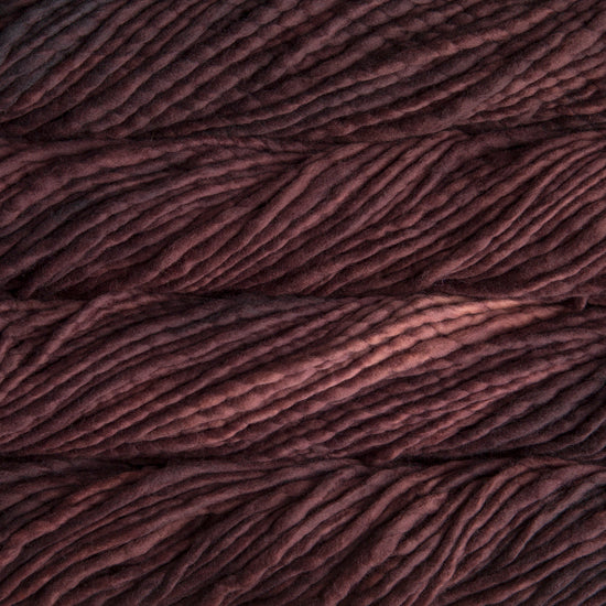 A close-up image of skeins of Malabrigo Rasta yarn in dark brown, displaying the texture and color variation.