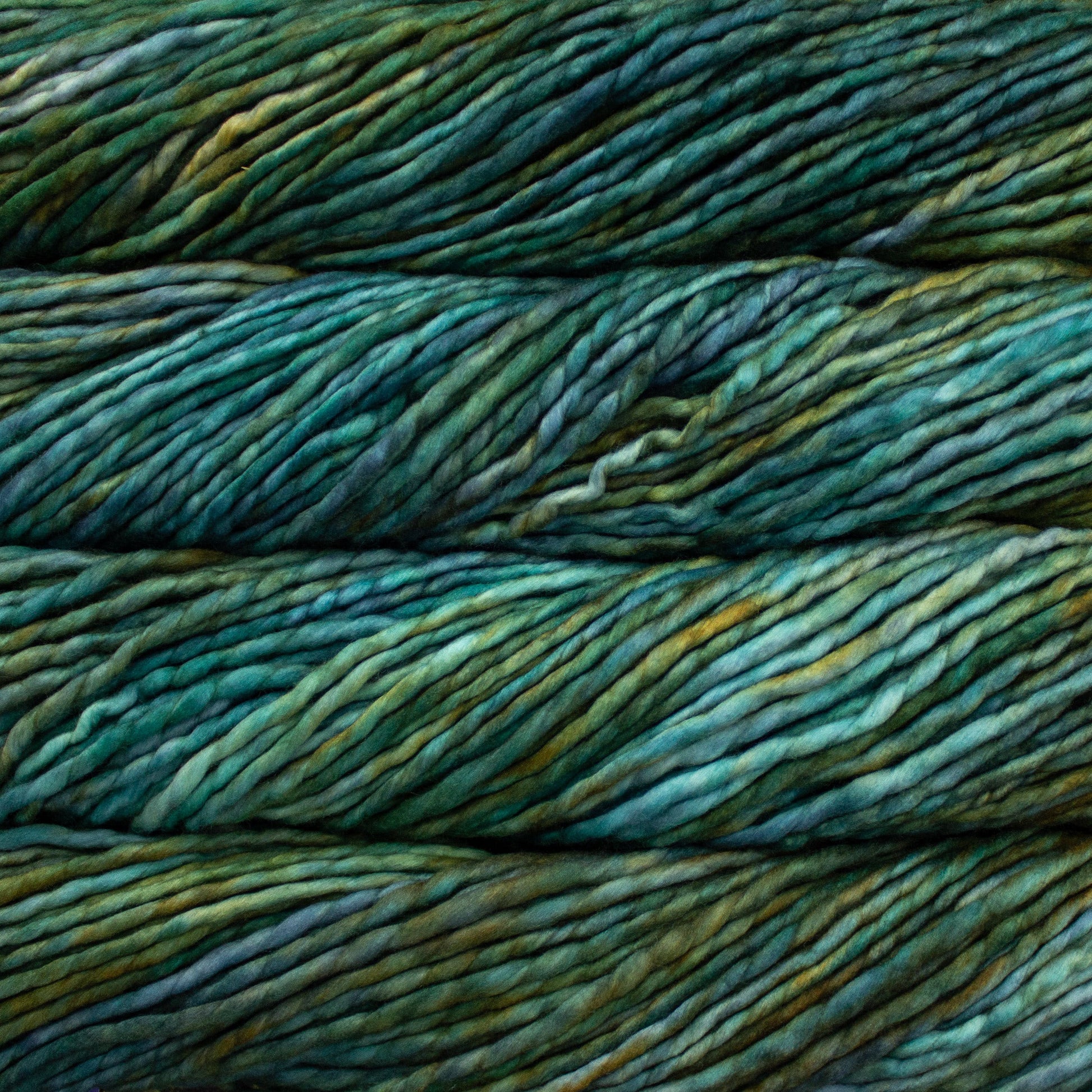A close-up image of skeins of Malabrigo Rasta yarn in shades of teal and dark green, displaying the texture and color variation.