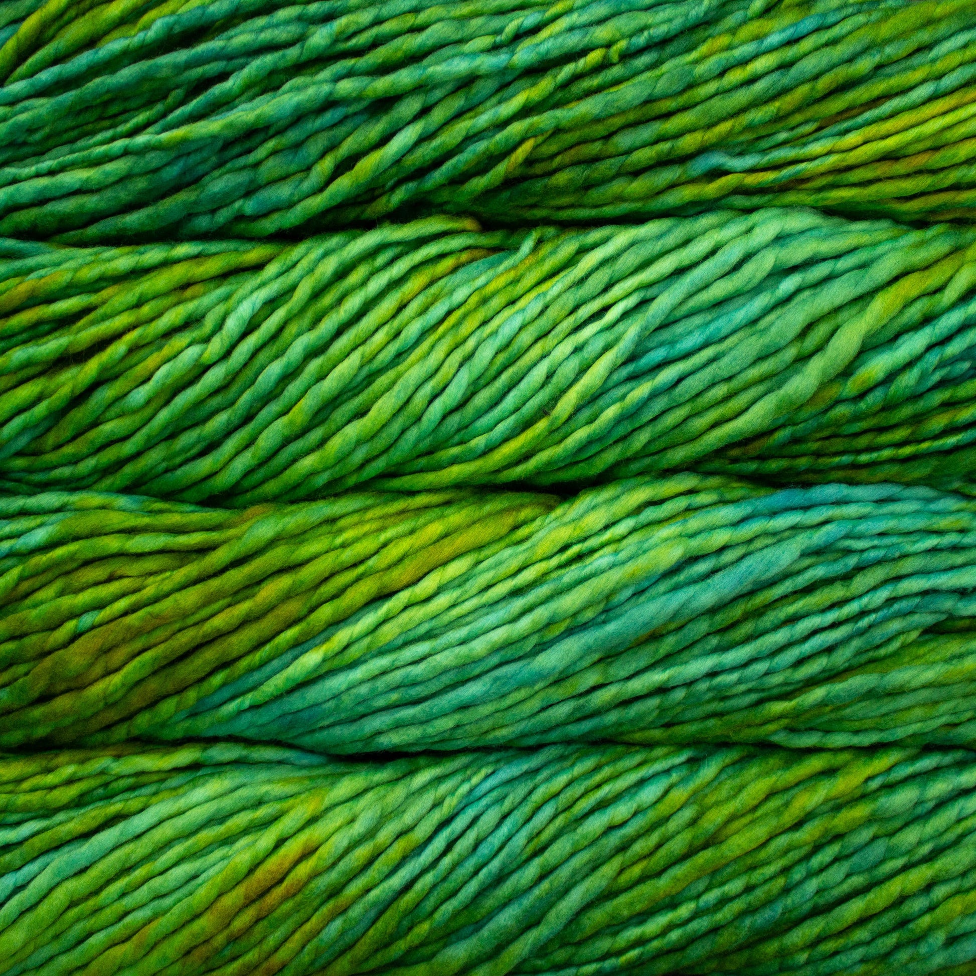 A close-up image of skeins of Malabrigo Rasta yarn in bright green shades, displaying the texture and color variation.