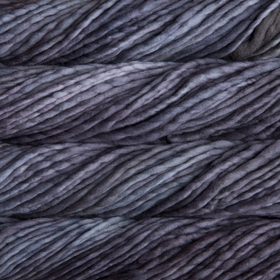 A close-up image of skeins of Malabrigo Rasta yarn in shades of gray and purple, displaying the texture and color variation.