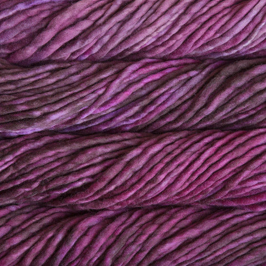 A close-up image of skeins of Malabrigo Rasta yarn in shades of purple and pink, displaying the texture and color variation.