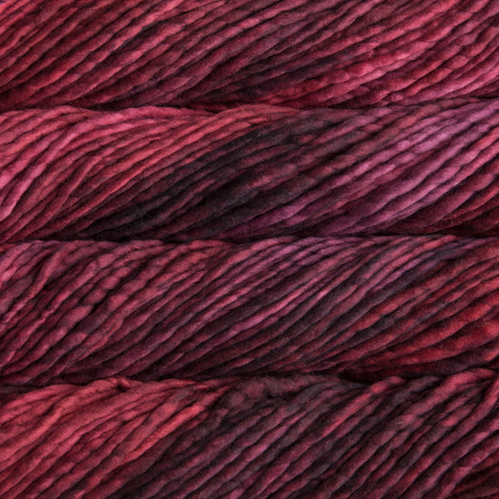 A close-up image of skeins of Malabrigo Rasta yarn in dark red shades, displaying the texture and color variation.