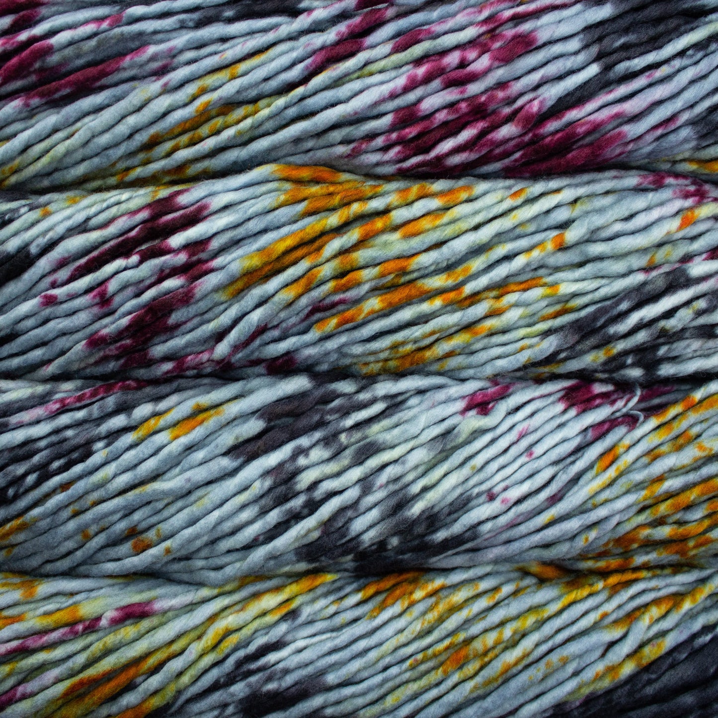 A close-up image of skeins of Malabrigo Rasta yarn in pale gray, charcoal, orange, and magenta, displaying the texture and color variation.