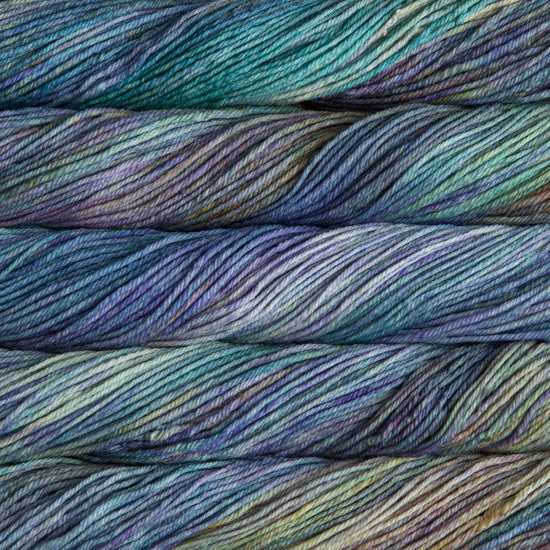 A close up of skeins of Malabrigo Rios worsted weight yarn in blue teal, yellow, and grey colors