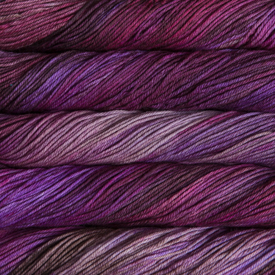 A close up of skeins of Malabrigo Rios worsted weight yarn in light and dark purple, mauve and brown colors