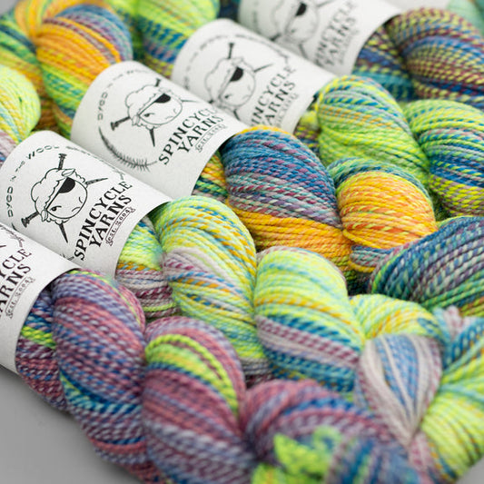 Multiple skeins of multicolored yarn arranged together, with labels showing the brand 'Spincycle Yarns'.